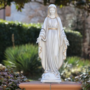 May include: White statue of the Virgin Mary with a gold trim on her robe. The statue is standing on a base with the words "MEDJUGORJE" inscribed on it.