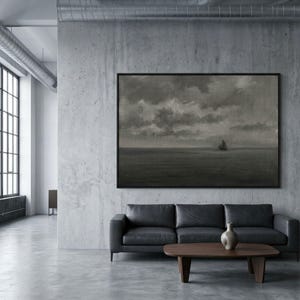 May include: A framed monochrome painting of a sailboat on the sea under a cloudy sky hangs above a black leather sofa. A wooden coffee table and a decorative vase are in front of the sofa. The room has a modern, minimalist design.