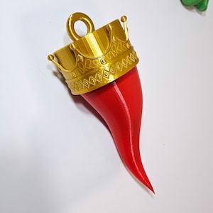 May include: A red, 3D printed horn with a gold crown on top. The horn is pointed at the tip and has a smooth, glossy finish.