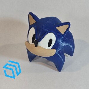 Pode incluir: Uma figura de Sonic the Hedgehog impressa em 3D de cor azul e marrom. A figura est&aacute; em uma pose de corrida com a cabe&ccedil;a inclinada para baixo e os olhos fechados.