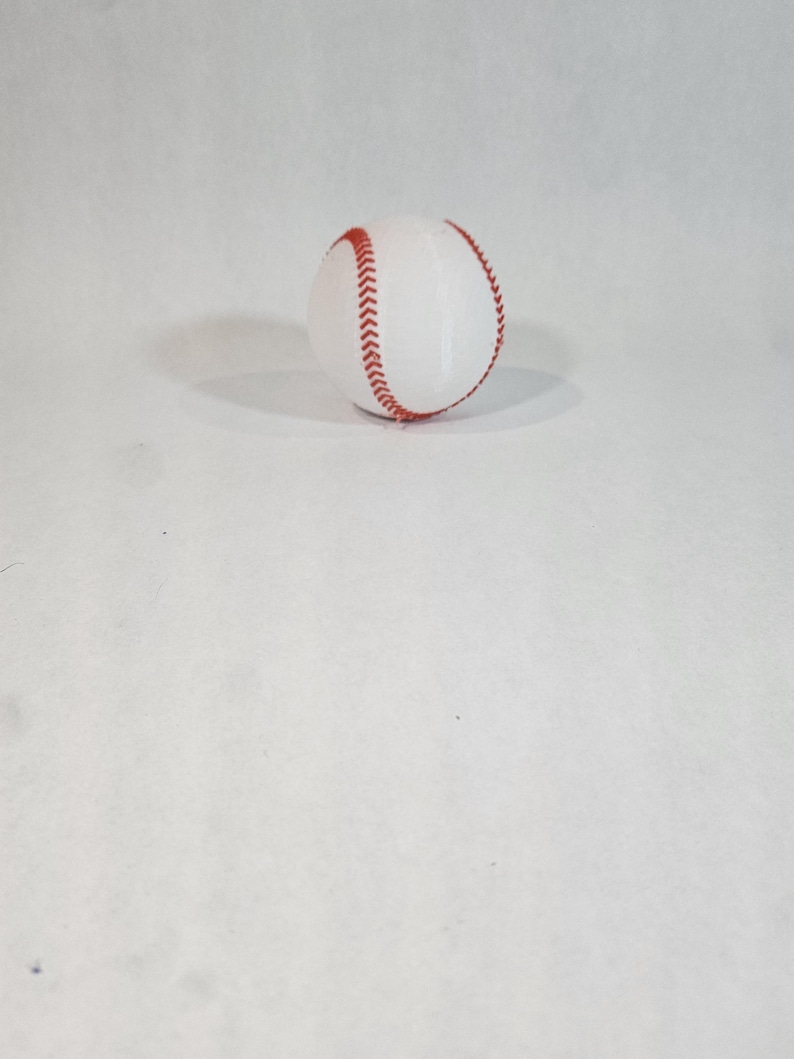 Pode incluir: Uma bola de beisebol branca com costuras vermelhas.