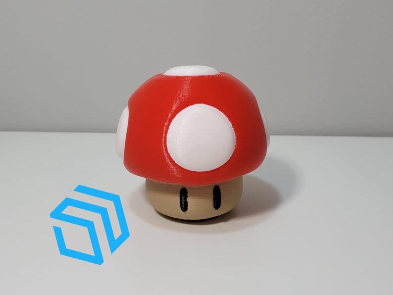 Pode incluir: Um cogumelo vermelho e branco impresso em 3D com um caule marrom e olhos pretos. O cogumelo &eacute; um personagem popular de videogame.