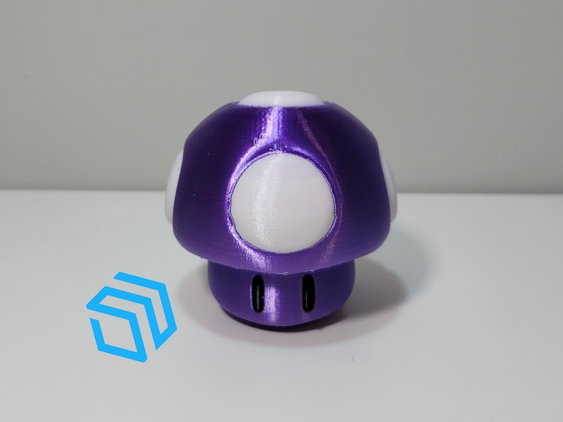 Pode incluir: Um brinquedo em forma de cogumelo roxo e branco. O cogumelo tem um acabamento roxo met&aacute;lico brilhante e manchas brancas.