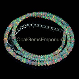 May include: A white opal beaded necklace with a silver clasp. The beads are iridescent and show flashes of green, blue, and pink.