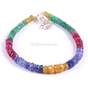 May include: A rainbow gemstone bracelet with a silver clasp. The bracelet features green, red, blue, and yellow gemstones.