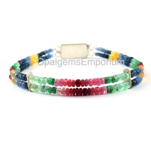 May include: A multi-colored gemstone bracelet with blue, green, red, and yellow beads. The bracelet is made of silver and has a clasp closure. "OpalgemsEmporium" is printed on the clasp.