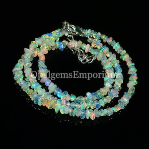 Peut inclure: Un collier à double rang de perles d'opale en forme d'écailles irisées. Le collier est de couleur argent et possède un fermoir argenté.