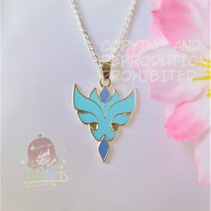 May include: A silver necklace with a pendant featuring a light blue and dark blue enamel design. The pendant has a stylized floral or abstract shape. The background is a white fabric with a pink flower in the corner. The text "COPYING AND REPRODUCTION PROHIBITED" is visible.