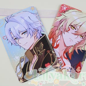 May include: Two anime-style character cards. One card features a character with light blue hair and a black and gold jacket. The other card shows a character with blonde hair and red markings. Both cards have a glossy finish and are decorated with stars and hearts.