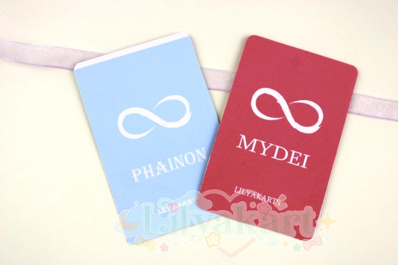 May include: Two rectangular cards, one light blue and one red, with a white infinity symbol. The blue card reads "PHAINON" and the red card reads "MYDEI". The cards are from "LILYAKARTS".