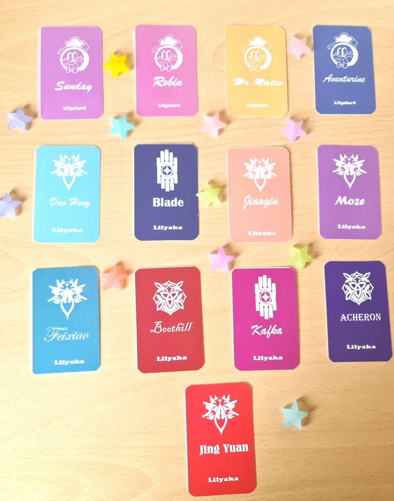 May include: A collection of colorful trading cards with character names and logos, including "Sunday," "Robin," and "Blade." Each card has a unique design and is accompanied by star-shaped decorations.