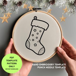 Puede incluir: Un diseño de calcetín navideño en blanco y negro sobre una tela color crema estirada dentro de un bastidor de bordado de madera. El calcetín está decorado con estrellas y círculos. El texto en la imagen dice "PDF TEMPLATE PATTERN ONLY INSTANT DOWNLOAD" y "HAND EMBROIDERY TEMPLATE PUNCH NEEDLE TEMPLATE."