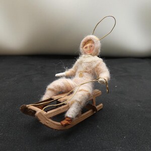 Rara figura antigua de algodón de un niño en trineo con cara de cartón en la década de 1900. Rara figura coleccionable de un niño en trineo navideño.