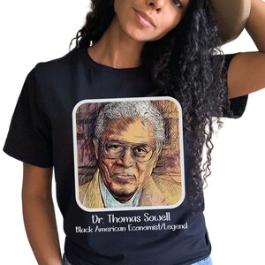 May include: Black t-shirt featuring a portrait of Dr. Thomas Sowell, an American economist and author. The text "Dr. Thomas Sowell Black American Economist/Legend" is printed below the portrait.
