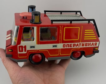 May include: Red toy fire truck with a black ladder, yellow stripes, and the word "ОПЕРАТИВНАЯ" on the side. The truck has a white number "01" on the side.