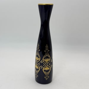 May include: A tall, navy blue vase with a gold rim and decorative gold floral patterns. The vase has a slender, elongated shape, widening slightly towards the base. The gold design adds a touch of elegance to the dark blue ceramic.