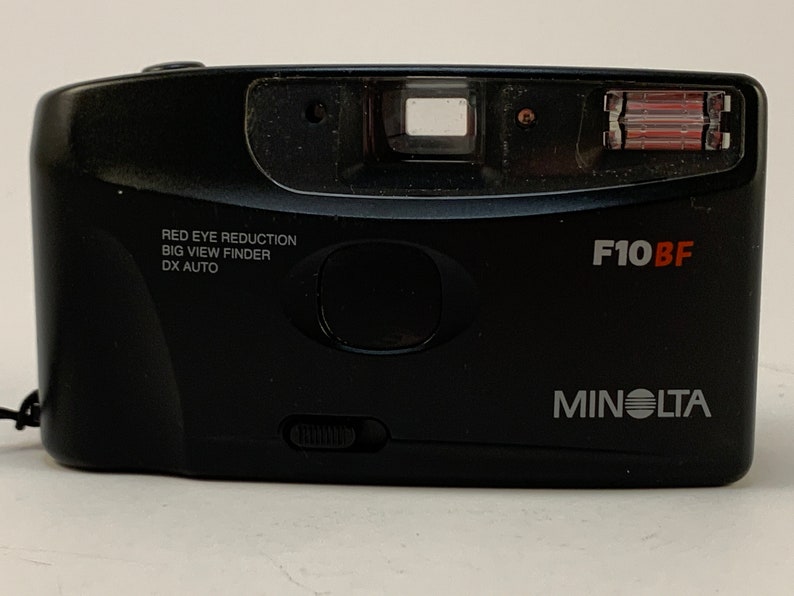 May include: A black Minolta F10BF point-and-shoot camera with a red eye reduction feature, a big view finder, and DX auto settings.