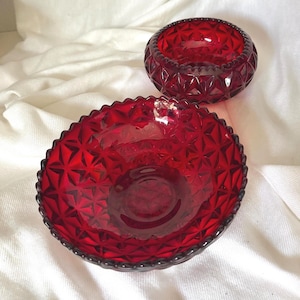 May include: Two deep red glass bowls featuring a prominent diamond-cut geometric pattern across the exterior surface. Each bowl has a scalloped, beaded rim and a circular base, showcasing a vibrant, translucent ruby color throughout the glass.