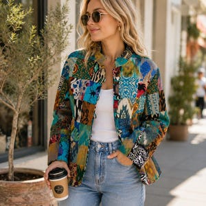 Puede incluir: Una chaqueta acolchada de manga larga con un vibrante patr&oacute;n de retazos de varios estampados geom&eacute;tricos y florales en azul, verde, amarillo y marr&oacute;n. La chaqueta tiene cuello mao, cierre de botones, una camiseta blanca sin mangas y vaqueros.