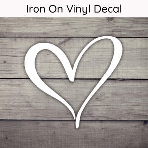 May include: White iron-on vinyl decal of a simple heart shape on a wood background.