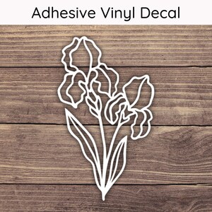 May include: White adhesive vinyl decal featuring a detailed outline of iris flowers and leaves. The decal is on a wooden background. The text "Adhesive Vinyl Decal" is at the top. Perfect for decorating various surfaces.