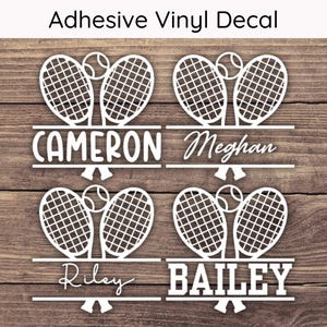 May include: White vinyl decal featuring tennis rackets and balls, with names Cameron, Meghan, Riley, and Bailey. The text "Adhesive Vinyl Decal" is at the top. The design is set against a wood grain background.
