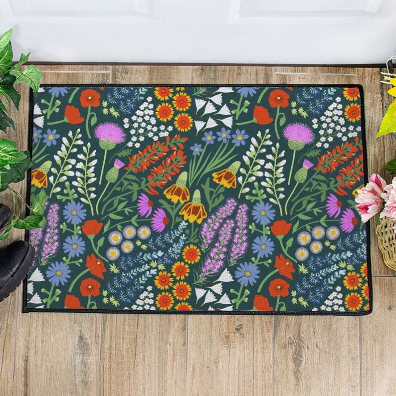 May include: A dark green doormat with a colorful floral pattern. The pattern features red, orange, yellow, pink, blue, and white flowers on a dark green background.