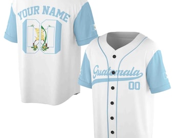May include: White baseball jersey with light blue sleeves. The jersey has "YOUR NAME" on the back and a number "00" on the front. The jersey also has the words "Guatemala" and the number "00" on the front.