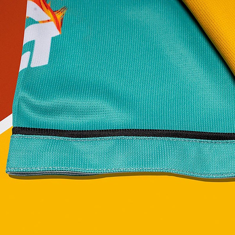 May include: Close-up of a teal fabric with a black trim. The fabric has a textured, woven appearance.