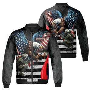 May include: A black bomber jacket featuring a detailed graphic of an American bald eagle with the American flag incorporated into the design. The jacket also includes an image of a soldier and the text "YOUR NAME".