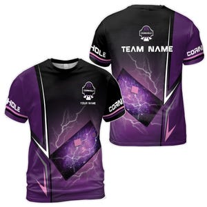 Könnte beinhalten: Lila und schwarzes Cornhole-Trikot mit einem weißen Blitz-Design und dem Text "CORNHOLE" und "TEAM NAME".