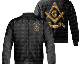 May include: Black bomber jacket with a gold Masonic symbol on the back and a smaller symbol on the left chest. The symbol includes a compass and square with the words "Hope" and "Charity" on a banner below. The jacket has a black and white geometric pattern.