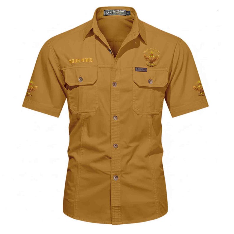Puede incluir: Camisa de manga corta color mostaza con dos bolsillos en el pecho y cierre de botones. La camisa presenta el texto "YOUR NAME" sobre el bolsillo izquierdo y un emblema en el bolsillo derecho. Emblemas adicionales est&aacute;n en las mangas. La camisa tiene cuello.