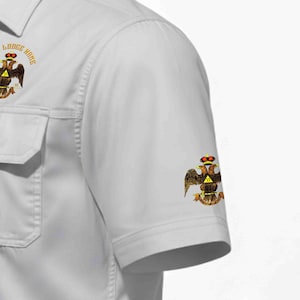 Puede incluir: Una camisa de manga corta gris claro con un emblema de &aacute;guila bic&eacute;fala con corona y el n&uacute;mero 33 en el pecho y la manga. El emblema del pecho incluye el texto Lodge Name en un arco circular sobre el gr&aacute;fico del &aacute;guila.