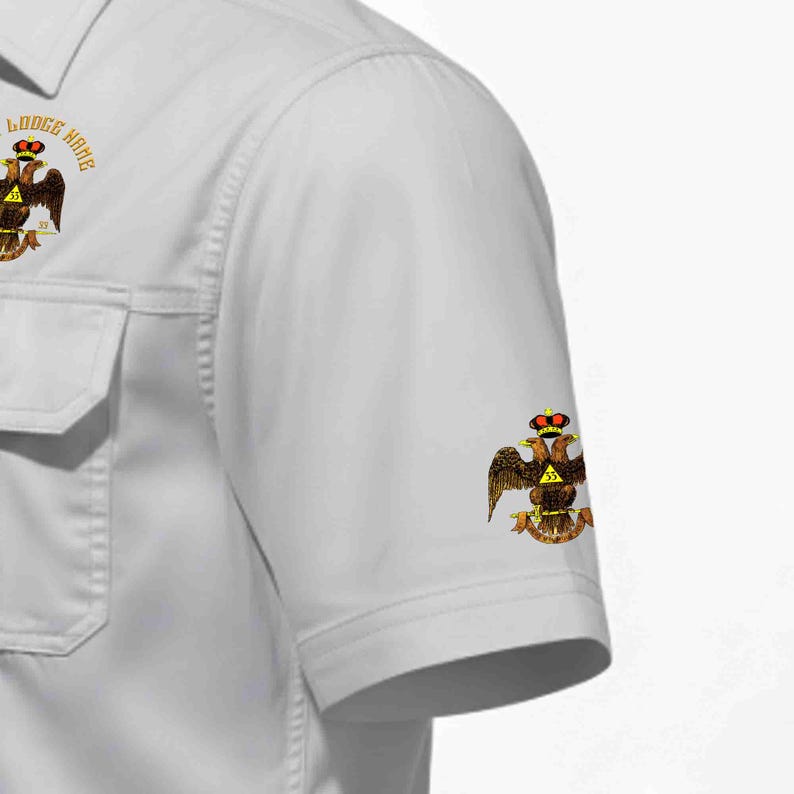 Puede incluir: Una camisa de manga corta gris claro con un emblema de &aacute;guila bic&eacute;fala con corona y el n&uacute;mero 33 en el pecho y la manga. El emblema del pecho incluye el texto Lodge Name en un arco circular sobre el gr&aacute;fico del &aacute;guila.