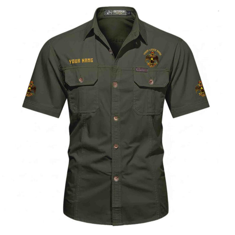 Puede incluir: Una camisa de manga corta abotonada de color verde oliva con dos bolsillos en el pecho con solapa. La camisa muestra el texto "YOUR NAME" en el pecho derecho, un emblema de &aacute;guila en el pecho izquierdo y emblemas iguales en ambas mangas.