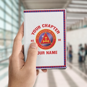 Puede incluir: Un portapasaporte blanco con un borde rojo, blanco y azul. La portada presenta el texto "YOUR CHAPTER" y "TO EVERYMAN HIS WAGES" en rojo, junto con un emblema circular y el texto "YOUR NAME".