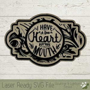 Op de afbeelding: Een zwart-wit ontwerp van een decoratief bord met een cirkel in het midden. De cirkel bevat de tekst "Ik heb een goed hart, maar deze mond".