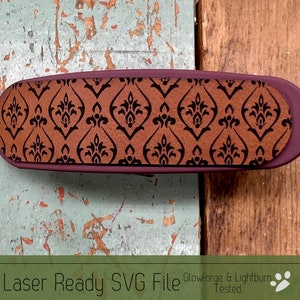 May include: A burgundy eyeglasses case with a brown and black damask pattern. The case is oval-shaped and has a textured surface. The text "Laser Ready SVG File" is at the bottom of the image.
