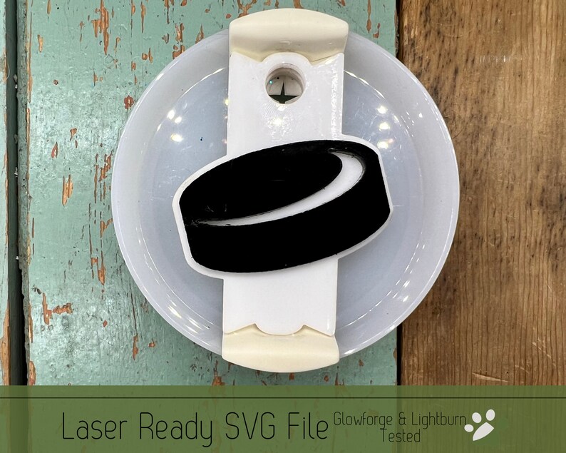 May include: A white plastic puck holder with a black hockey puck design. The holder has a small hole in the top for hanging. Glowforge & Lightburn Tested.
