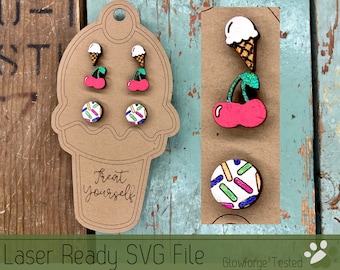 May include: A set of three laser-cut wooden earrings featuring a cherry with an ice cream cone, a cherry with a green stem, and a sprinkle-covered circle. The earrings are displayed on a brown paper cone with the text "Treat yourself".
