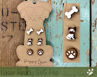 May include: A set of six laser-cut wooden earrings featuring dog-themed designs. The earrings include two bone shapes, two paw prints, and two French bulldog silhouettes. The earrings are displayed on a brown card with the text "Puppy Love".