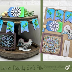 Op de afbeelding: Lasergesneden SVG-bestand voor een decoratieproject in landelijke stijl. Het ontwerp bevat een banner met de woorden "Bless Our Nest", een haan, een windmolen en een achtergrond van gaas.