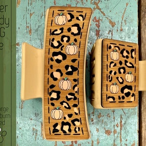 May include: Two wooden hair clips with a leopard print and pumpkin design. The clips are laser cut and ready to be used.