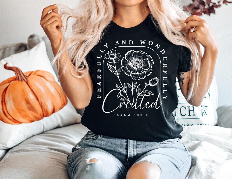 May include: Black t-shirt with a white floral design and the text "Fearfully and Wonderfully Created" with the scripture reference "Psalm 139:14".