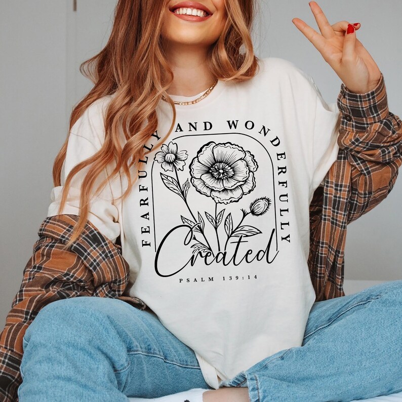 May include: A white long-sleeved shirt with a black floral design and the text "Fearfully and Wonderfully Created Psalm 139:14".