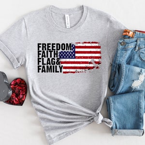 May include: Grey t-shirt with a distressed American flag graphic and the text "FREEDOM FAITH FLAG & FAMILY".