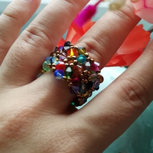 Könnte beinhalten: Ein bunter Perlenring mit goldfarbenem Draht und einer Vielzahl von Kristallperlen in Rot-, Blau-, Grün-, Lila- und Gelbtönen.