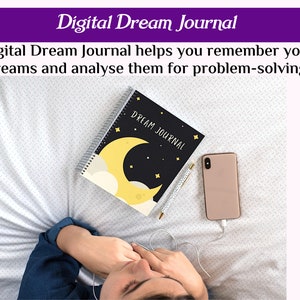 May include: A black and yellow notebook with the words "DREAM JOURNAL" on the cover. The notebook is lying on a white bedspread with a gold pen and a pink smartphone next to it. A person is lying on the bed with their head covered by a blue shirt.