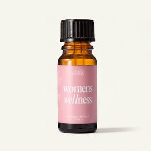 May include: A small amber glass bottle with a black ribbed screw cap, featuring a pink label with white text that reads Tyler Aromatherapy, womens wellness, and Essential Oil Blend 10ml. The bottle contains a liquid essential oil blend.